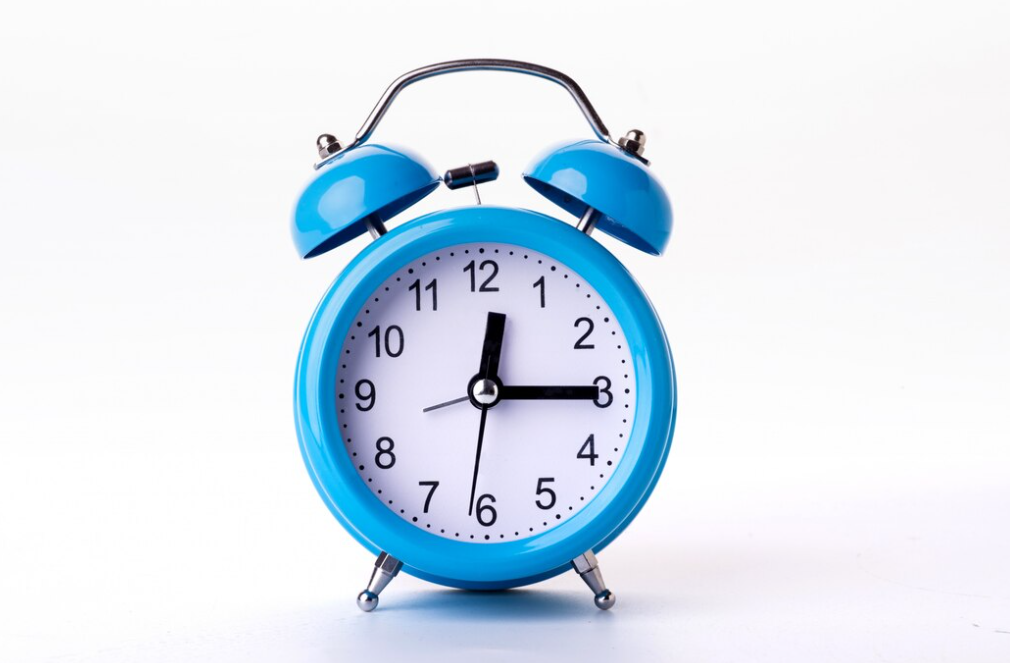 A blue alarm clock with a white face displaying the time, isolated against a white background